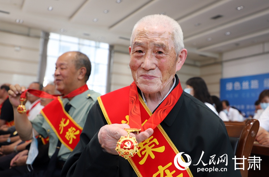 一位老党员代表展示自己的“光荣在党50年”纪念章。人民网 王文嘉摄