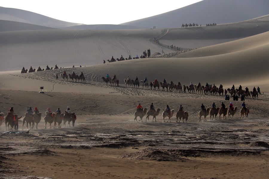 游客在甘肃省敦煌市鸣沙山月牙泉景区游览。 张晓亮摄