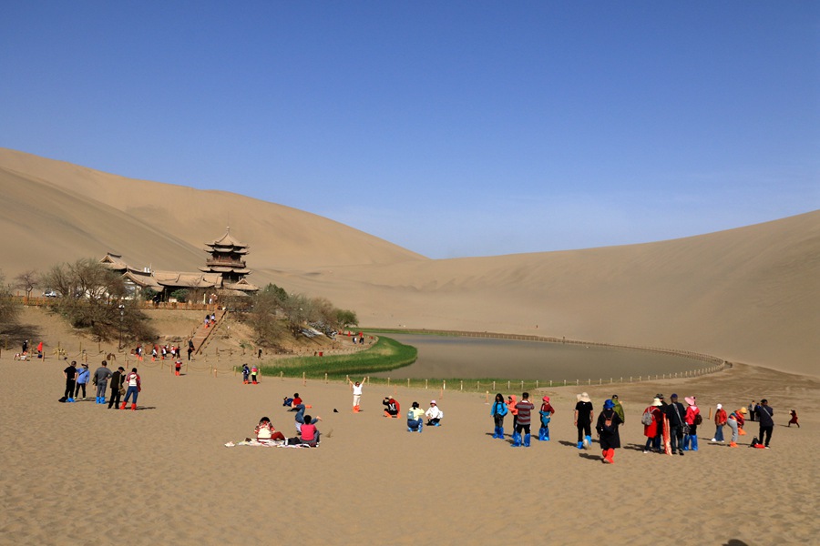 游客在甘肃省敦煌市鸣沙山月牙泉景区游览。 张晓亮摄