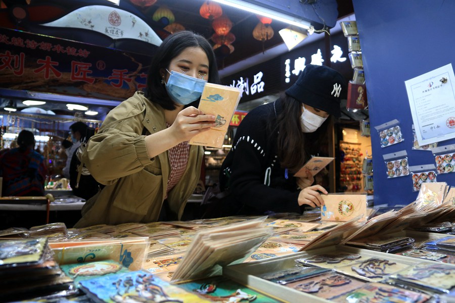游客在敦煌夜市欣賞選購敦煌文化元素書簽。張曉亮攝