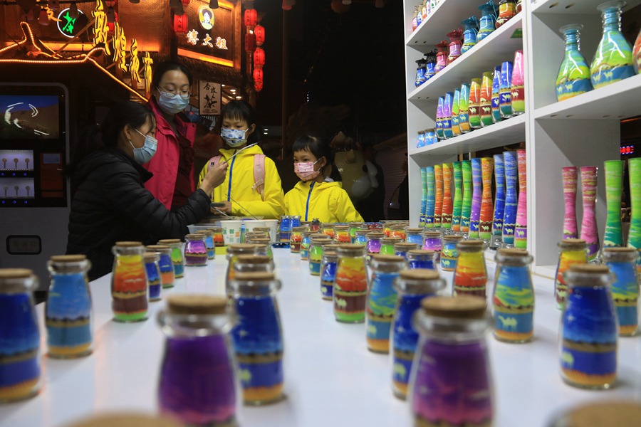 游客在敦煌夜市欣賞選購沙瓶畫。張曉亮攝