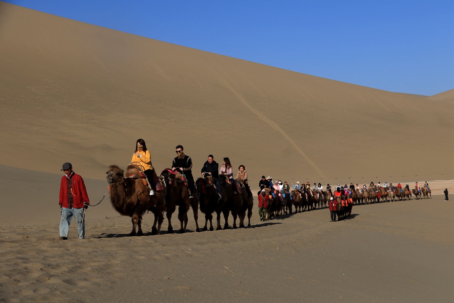 游客在甘肅省敦煌市鳴沙山月牙泉景區游覽。張曉亮攝
