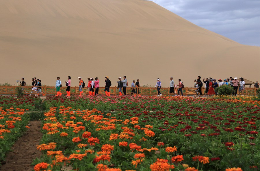 端午假期，游客在甘肃省敦煌市鸣沙山月牙泉景区游览。张晓亮摄