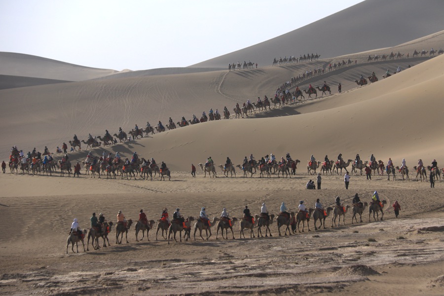端午假期，游客在甘肅省敦煌市鳴沙山月牙泉景區游覽。張曉亮攝