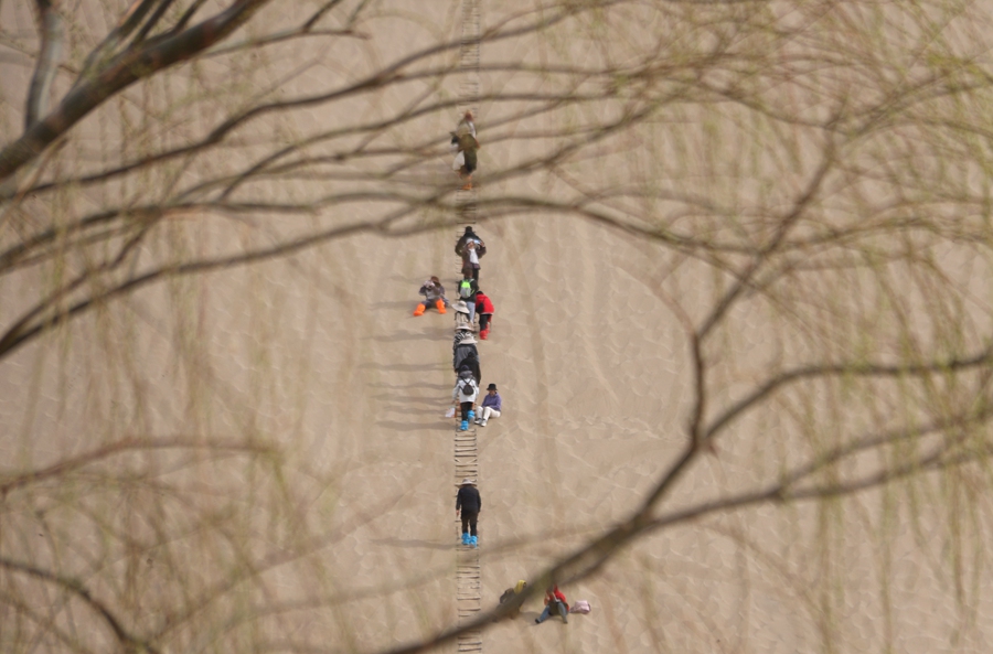 3月24日，游客在甘肅省敦煌市鳴沙山月牙泉景區游覽。張曉亮攝