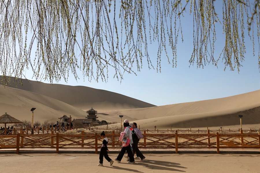 3月24日，游客在甘肅省敦煌市鳴沙山月牙泉景區游覽。張曉亮攝