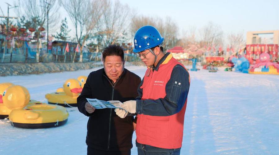 国网酒泉供电公司员工针对造雪机等设备向冰雪乐园工作人员讲解安全用电知识。裴勇峰摄