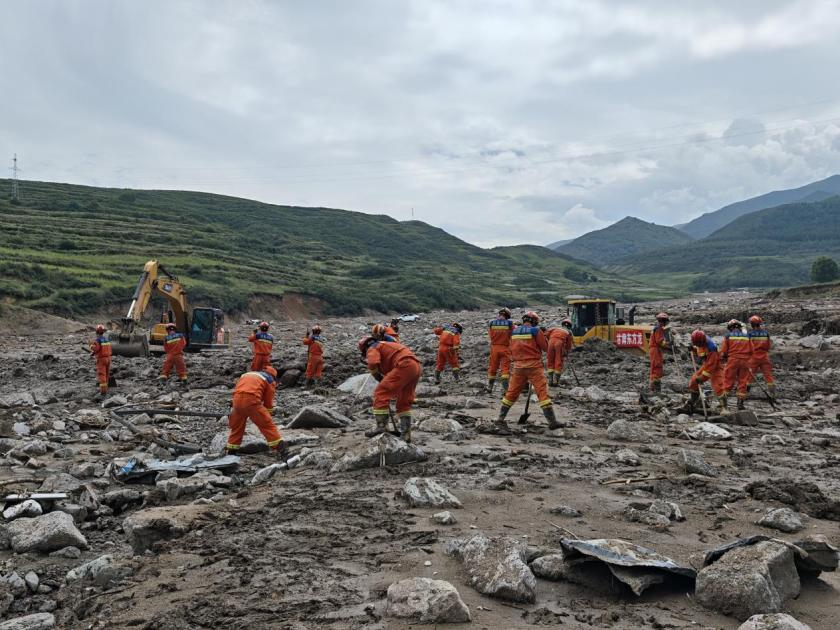 8月10日15时，消防救援人员在灾情严重的马坡乡马莲滩村河沟区域，联合重型机械围绕一处塌陷建筑展开搜救。甘肃消防供图