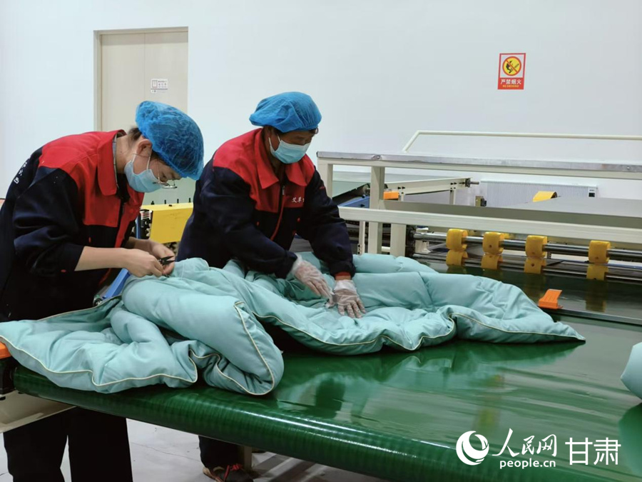 工作人员整理刚刚制作好的艾草被。人民网记者 焦隆摄