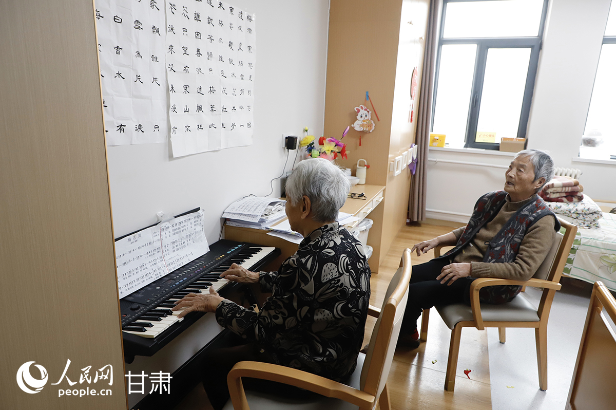 鋼琴旁，王秀萍老人和老友在專注彈唱。人民網記者 焦隆攝
