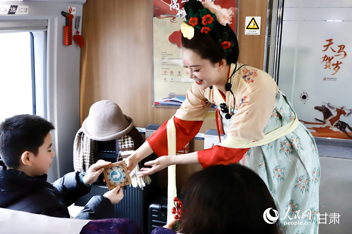 敦煌研究院工作人员向旅客赠送文创礼品。人民网记者 焦隆摄