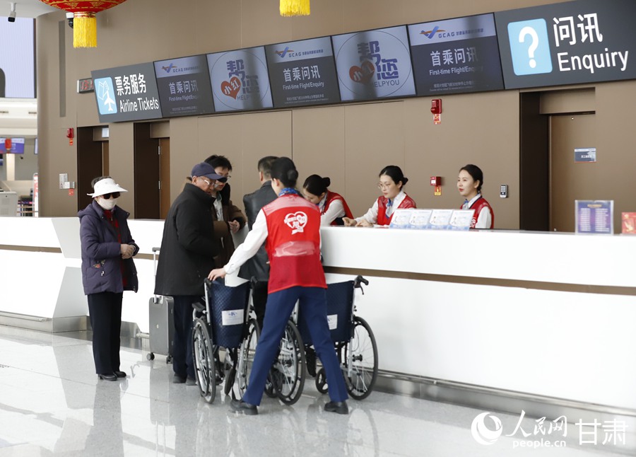 兰州中川国际机场“小红帮您”工作人员护送老年旅客登机。人民网记者 焦隆摄