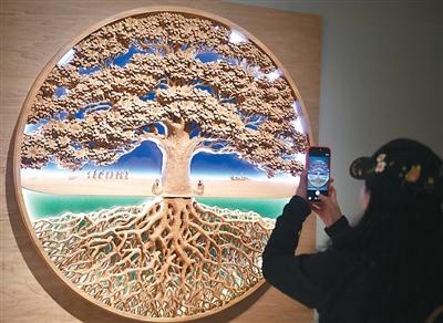 参观者在中国美术馆拍摄展出的木雕展品《生万物》。新华社记者 鲁 鹏摄