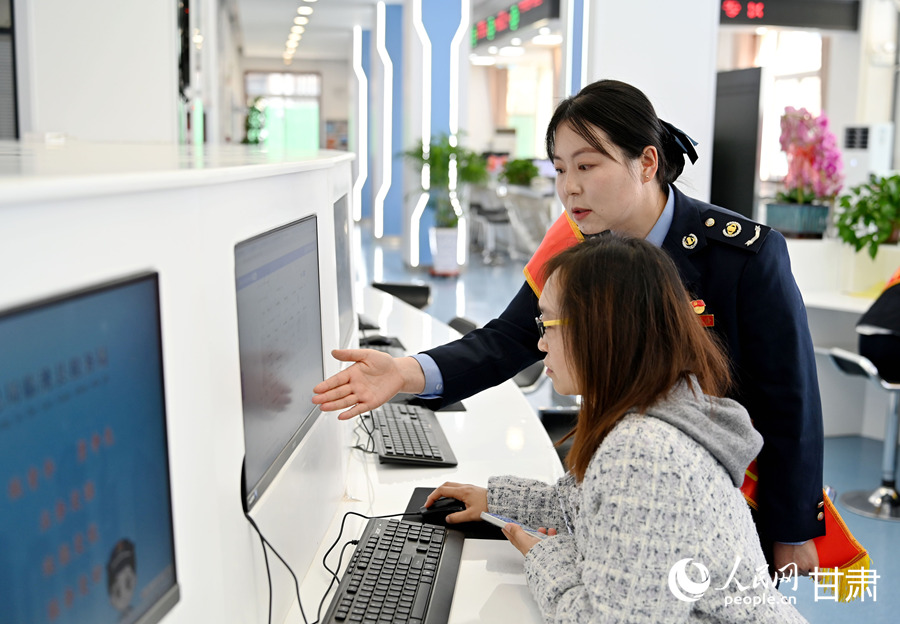 在临洮县税务局第一税务分局办税服务大厅自助办税区，税务工作人员指导群众办理业务。人民网 席娟娟摄