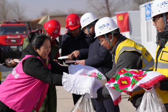 12月24日，青海省海东市民和县中川乡美一村志愿者代表当地群众为安置点建设施工单位送上鞋垫、枕套表达感谢。人民网记者 甘海琼摄