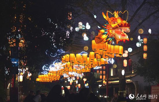 2月10日，游客在杭州西溪濕地的“百丈龍燈”前打卡留念。“百丈龍燈”位於西溪濕地內蔣村集市慢生活街區，長40余米，蜿蜒盤旋與周邊各色花燈交相輝映。人民網記者 郭揚攝 