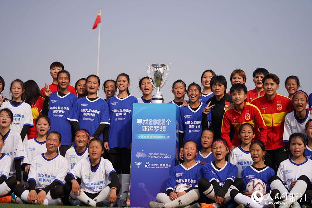 3月3日，校园女足的小球员们与中国女足在亚洲杯奖杯前合影。人民网 章勇涛摄