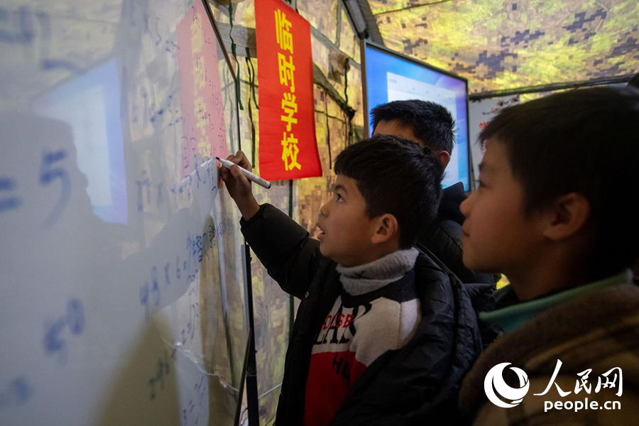 12月22日，在積石山縣大河家鎮大河村安置點，陸軍76集團軍某旅搭建的“臨時學校”內，小學生正在做題學習。人民網記者 翁奇羽攝